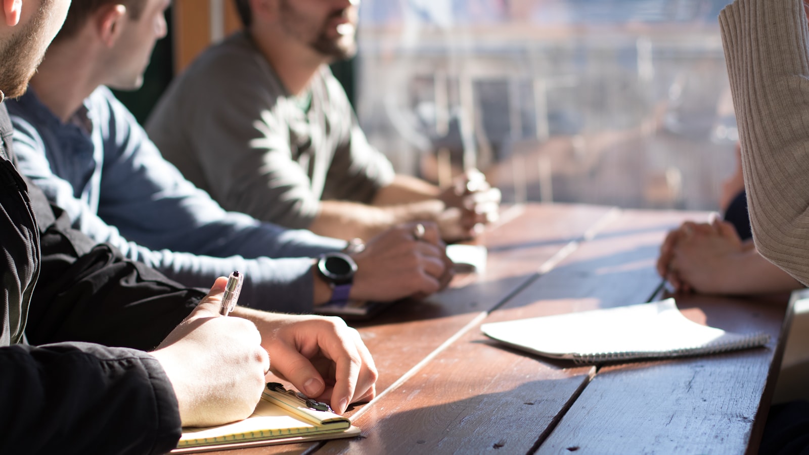 Two people sitting across a table in a bright office during a job interview.
